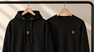 Schwarzer Hoodie und Sweatshirt von BITVESTIS mit goldenem Bitcoin-Stick auf Holzbügeln – Nahaufnahme.